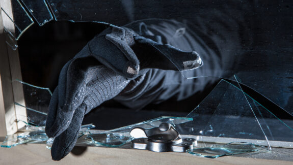 An image of a gloved hand breaking through a window