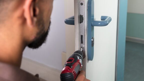 An image of a man using a drill to unscrew a lock