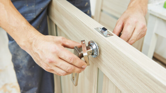 An image of a man fitting a handle to a wooden door